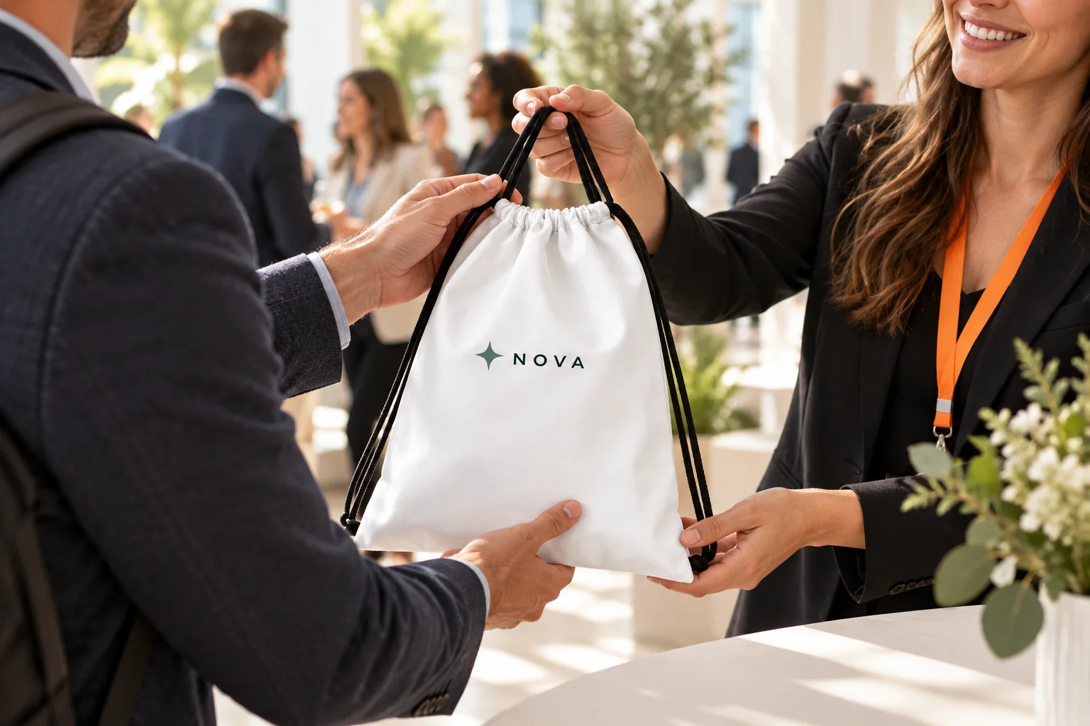 An event host handing a white branded drawstring bag to an attendee at a networking event.